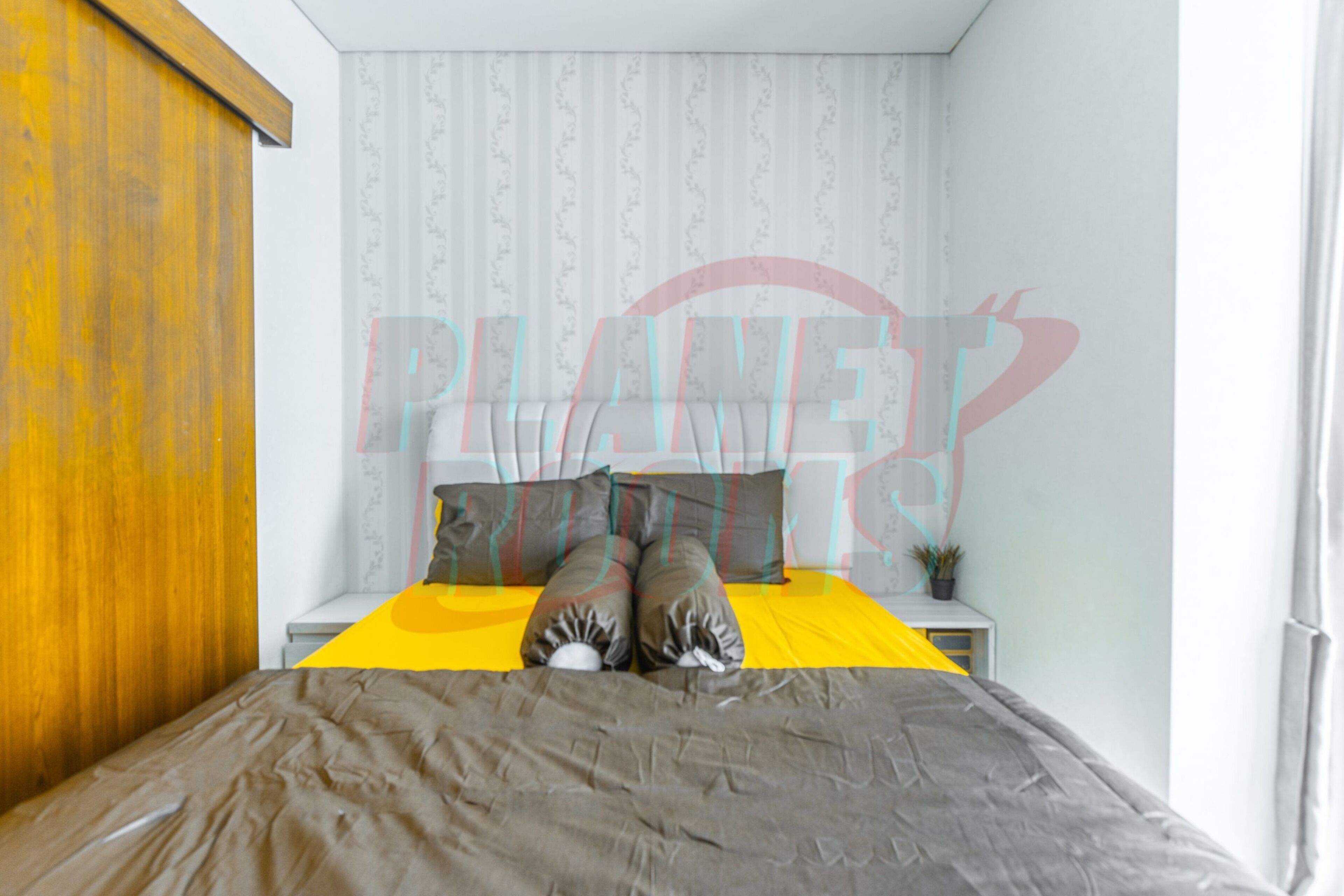 Un dormitorio con una cama, almohadas, una mesita de noche y una ventana.