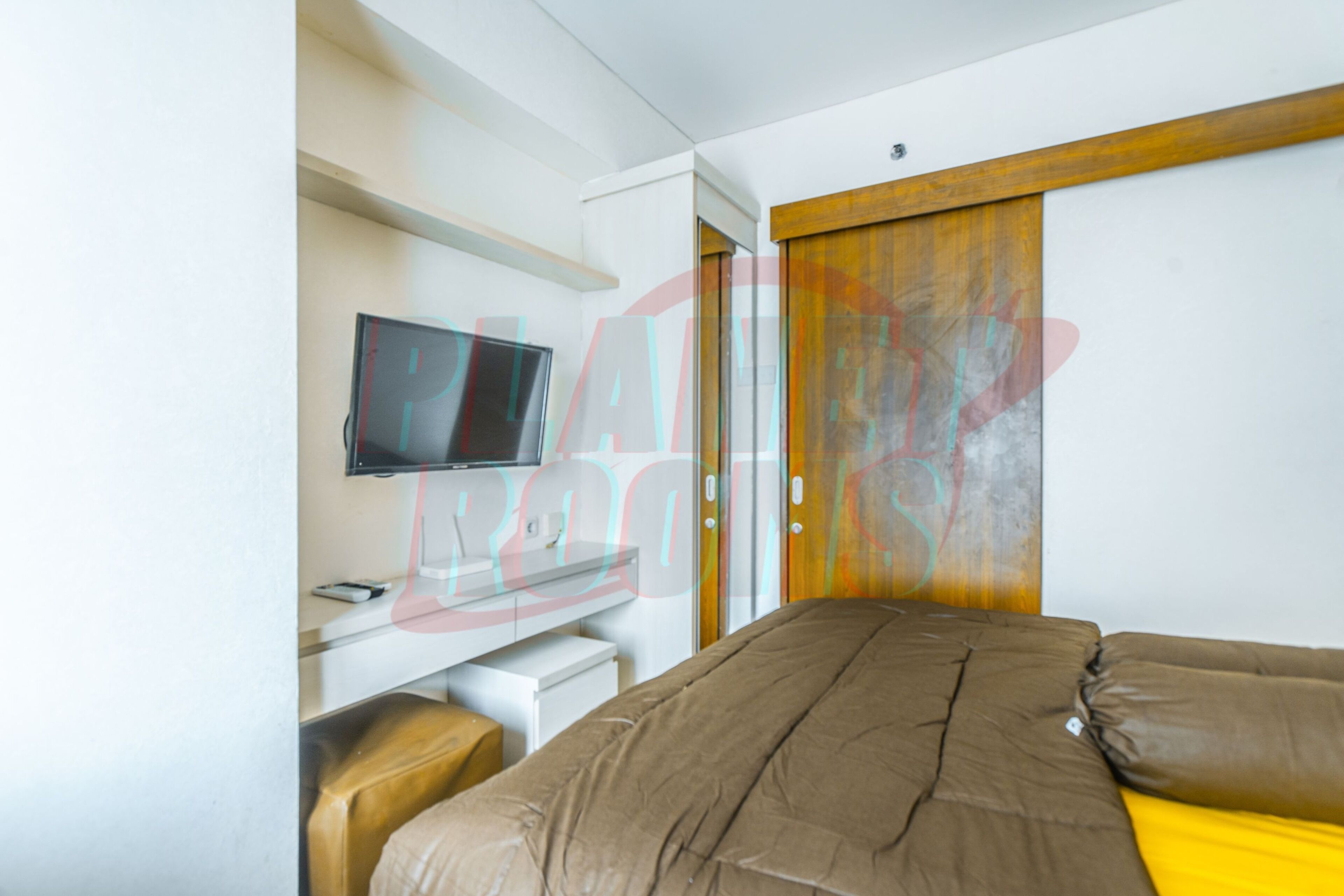 Une chambre d’hôtel moderne équipée d’un lit, d’un bureau avec un téléviseur à écran plat et d’une porte coulissante.
