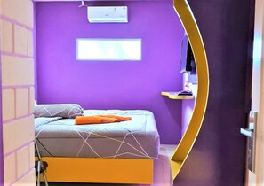 A room with a bed, a window, and a wall-mounted air conditioner.