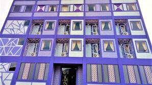 A multi-story building with a purple facade, featuring geometric patterns and multiple windows with curtains. - Ungu Hotel Garut (Garut)
