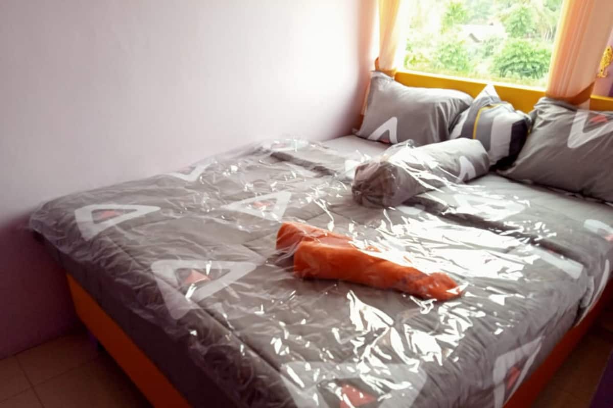 Uma cama com colcha cinza e branca estampada, almofadas e um cobertor.