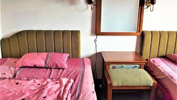 A hotel room with two beds, a small wooden table, and a mirror on the wall.