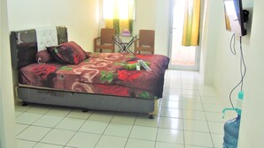 Un dormitorio con cama, televisión, silla y mesa.