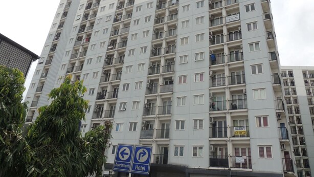 Un immeuble d’habitation de grande hauteur, doté de nombreux balcons et d’une enseigne indiquant la direction d’un appartement et d’un hôtel.