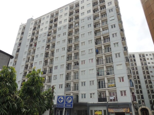 A multi-story residential building with balconies, a sign indicating an apartment and hotel, and a visible storefront below.