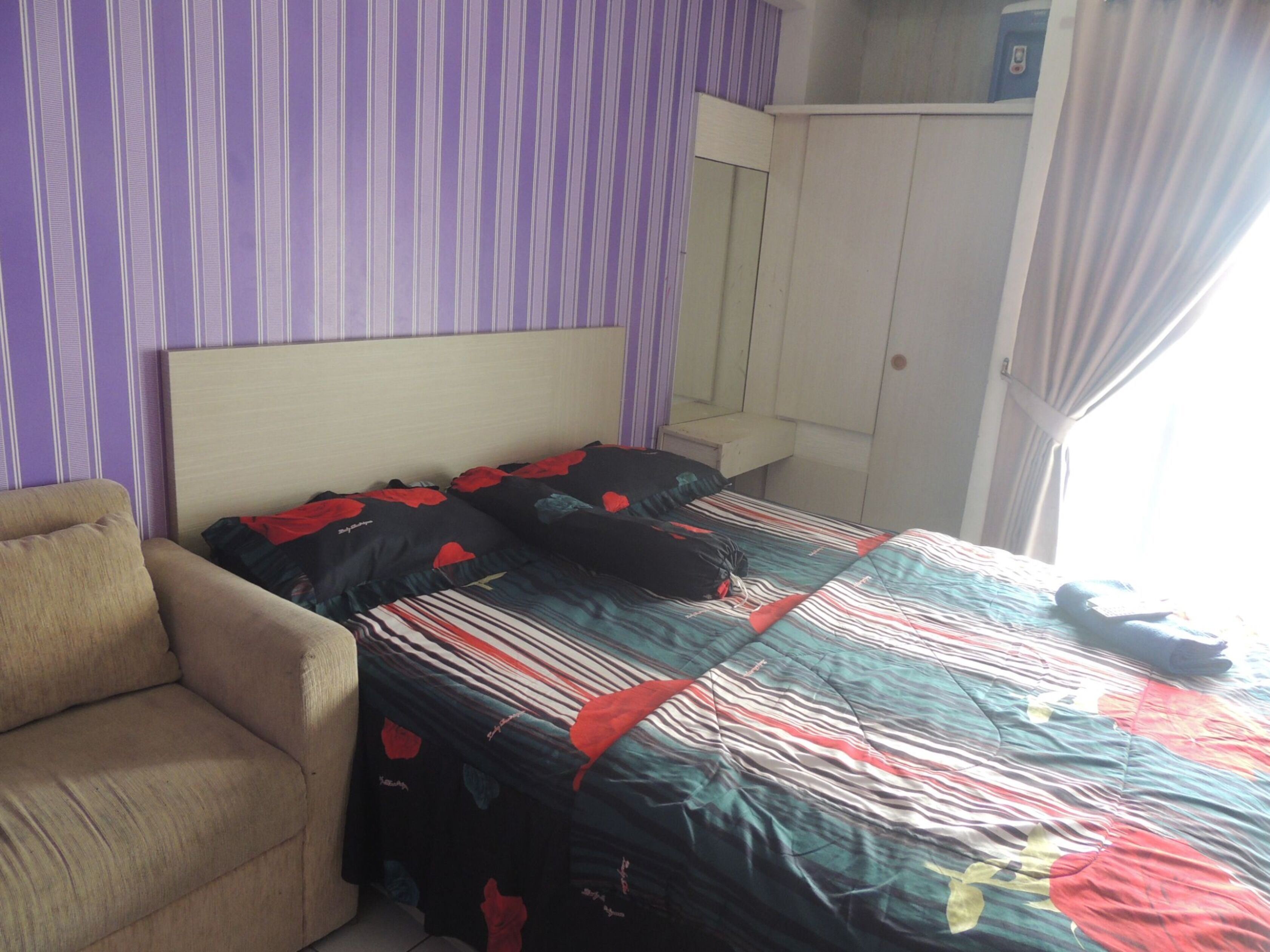 A bedroom with a bed, a chair, and a wardrobe.