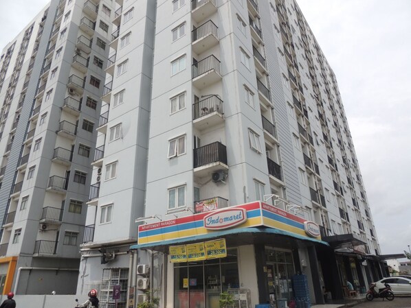 A multi-story building with balconies and a storefront labeled 'Indomaret'. - Alexandria Room at Apartement Paragon Village (Curug)