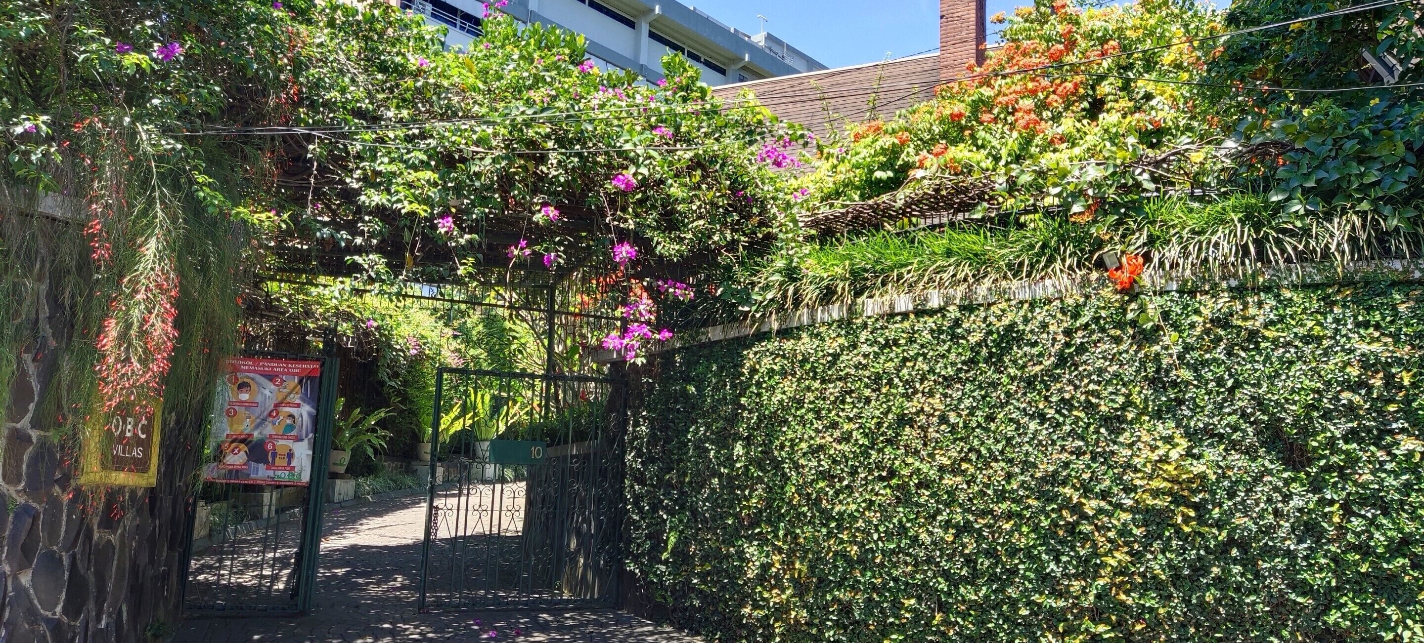 A garden gate with a sign reading "OBC Villas" and a number "10" on a metal gate.