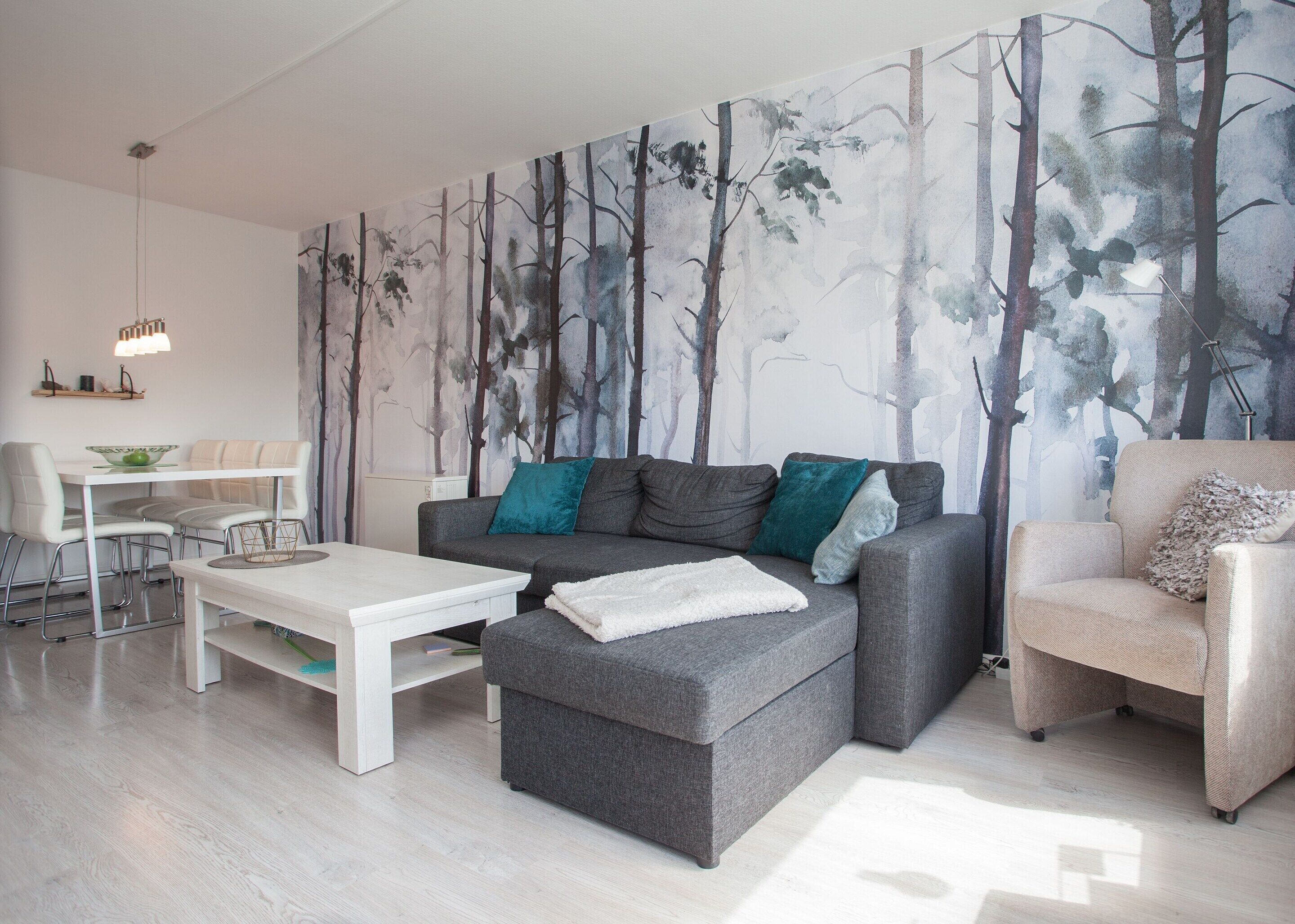 Ein modernes Wohnzimmer mit grauem Sofa, weißem Couchtisch und einer Essecke mit weißem Tisch und Stühlen.