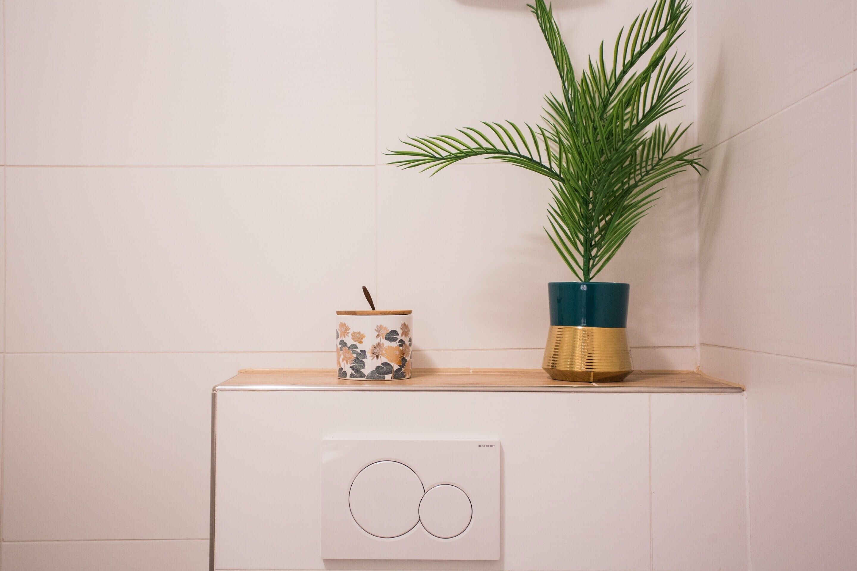 A bathroom with a white cabinet, a decorative plant, and a small container with a straw.