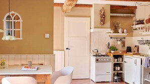 A kitchen with a stove, cabinets, and a dining area with a table and chairs.