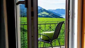 Un balcone con una sedia e un cuscino, con vista su un paesaggio verde e montagne.