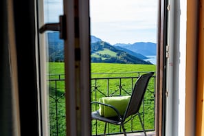 Ein Balkon mit Stuhl und Kissen mit Blick auf eine grüne Landschaft und Berge.