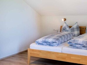 Ein Schlafzimmer mit einem hölzernen Bett, karierten Bettwäsche, einem Nachttisch und einer Wandleuchte.