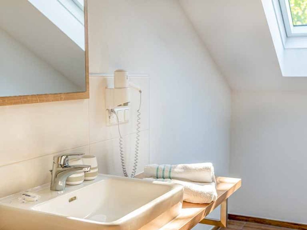 Un baño moderno con un espejo grande, un lavabo, un perchero para toallas y una ducha.