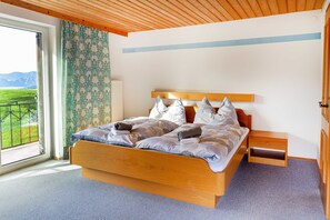 Un dormitorio con una cama de madera, una mesita de noche y vistas a un paisaje verde por una ventana.