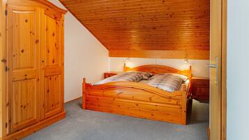 Une chambre à coucher avec un lit en bois, une armoire et un plafond en pente.