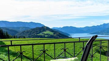 Un balcon doté d’une balustrade en métal, d’une chaise verte et offrant une vue sur un lac entouré de montagnes.