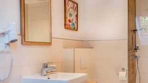 Ein Badezimmer mit Waschbecken, Spiegel, Dusche und Toilette.
