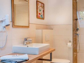 Ein Badezimmer mit Waschbecken, Spiegel, Dusche und Toilette.