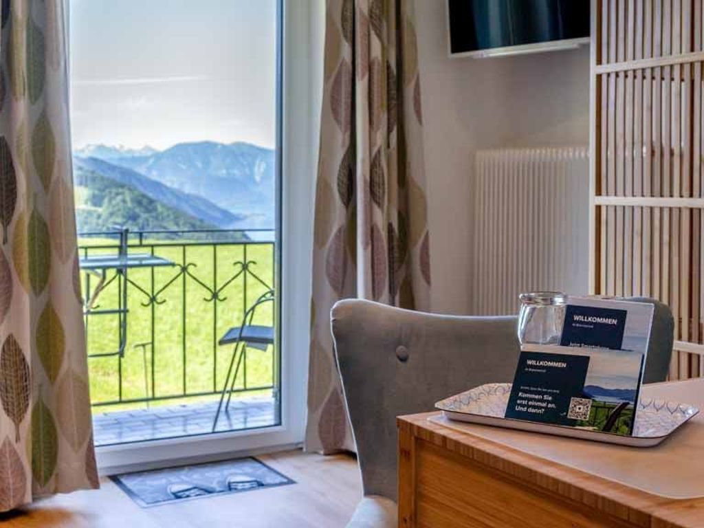 Een kamer met uitzicht op bergen, een laptop op een tafel en een welkomstbord.