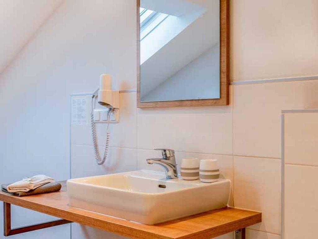 A bathroom with a white sink, a mirror, a towel, and a phone.