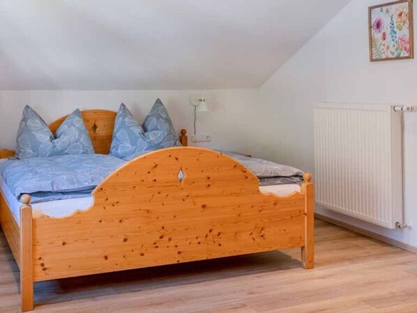 Una cama de madera con cabecera curvada, un radiador blanco y un aplique de pared.