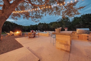 An outdoor patio with a grill, seating, and a fire pit.