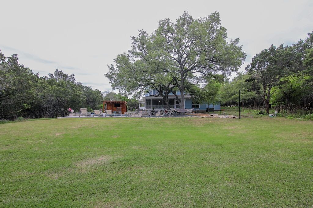 A house with a large lawn, a tree, and a small structure.