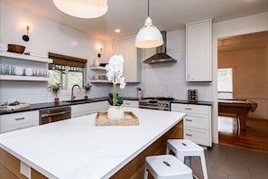 A modern kitchen with white cabinetry, a central island, and a hanging pendant light.