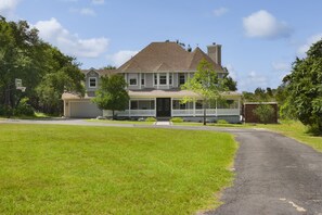 A two-story house with a front porch, a garage, and a driveway leading to the front door.