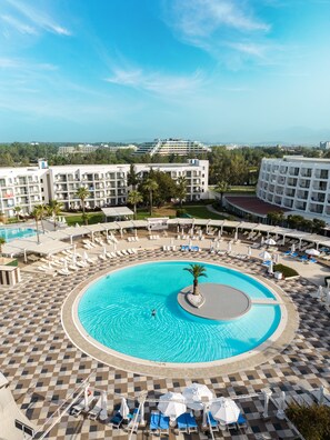 A resort with a large central pool, multiple lounge areas, and a view of surrounding buildings. - Kaya Side Hotel (Manavgat)