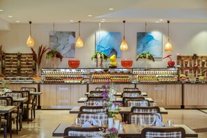 A restaurant with a long counter, multiple hanging lights, and a variety of food items displayed. - Kaya Side Hotel (Manavgat)
