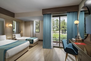 Quarto de hotel com duas camas, uma escrivaninha, uma cadeira e uma janela grande com cortinas.