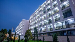 A multi-story hotel with a modern design, featuring balconies on each floor and a well-lit facade. - Hotel Terra (Neptun)