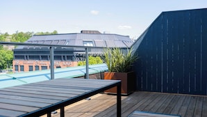 Terraza en la azotea con mesa de madera y plantas en macetas.