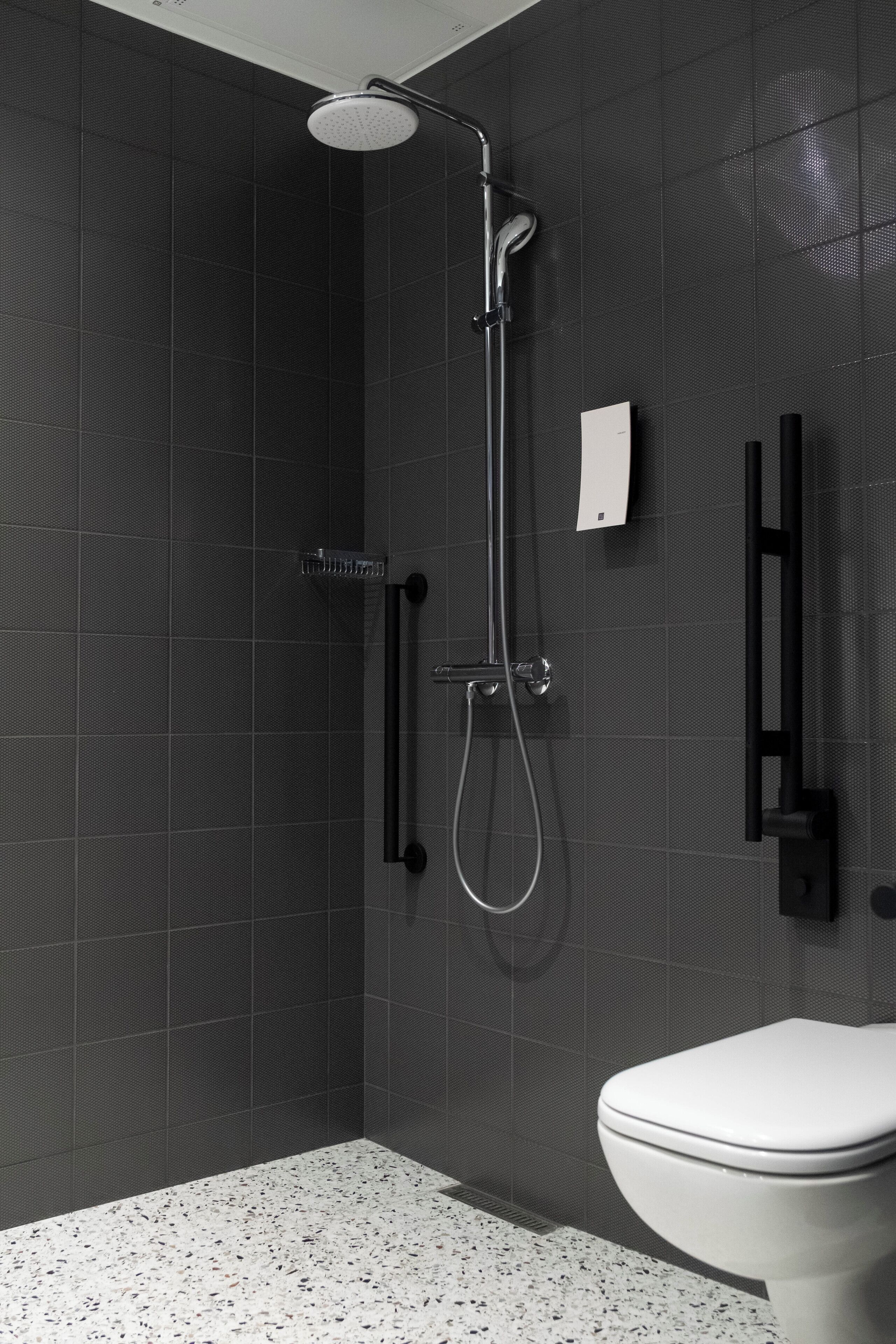 A modern bathroom with a shower, toilet, and a towel rack.