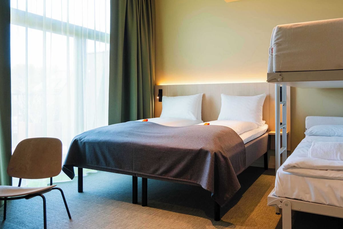 A hotel room with a bed, a chair, and a bunk bed.