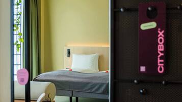Ein Hotelzimmer mit Bett, Stuhl, Schreibtisch und einem Fenster mit Vorhängen.