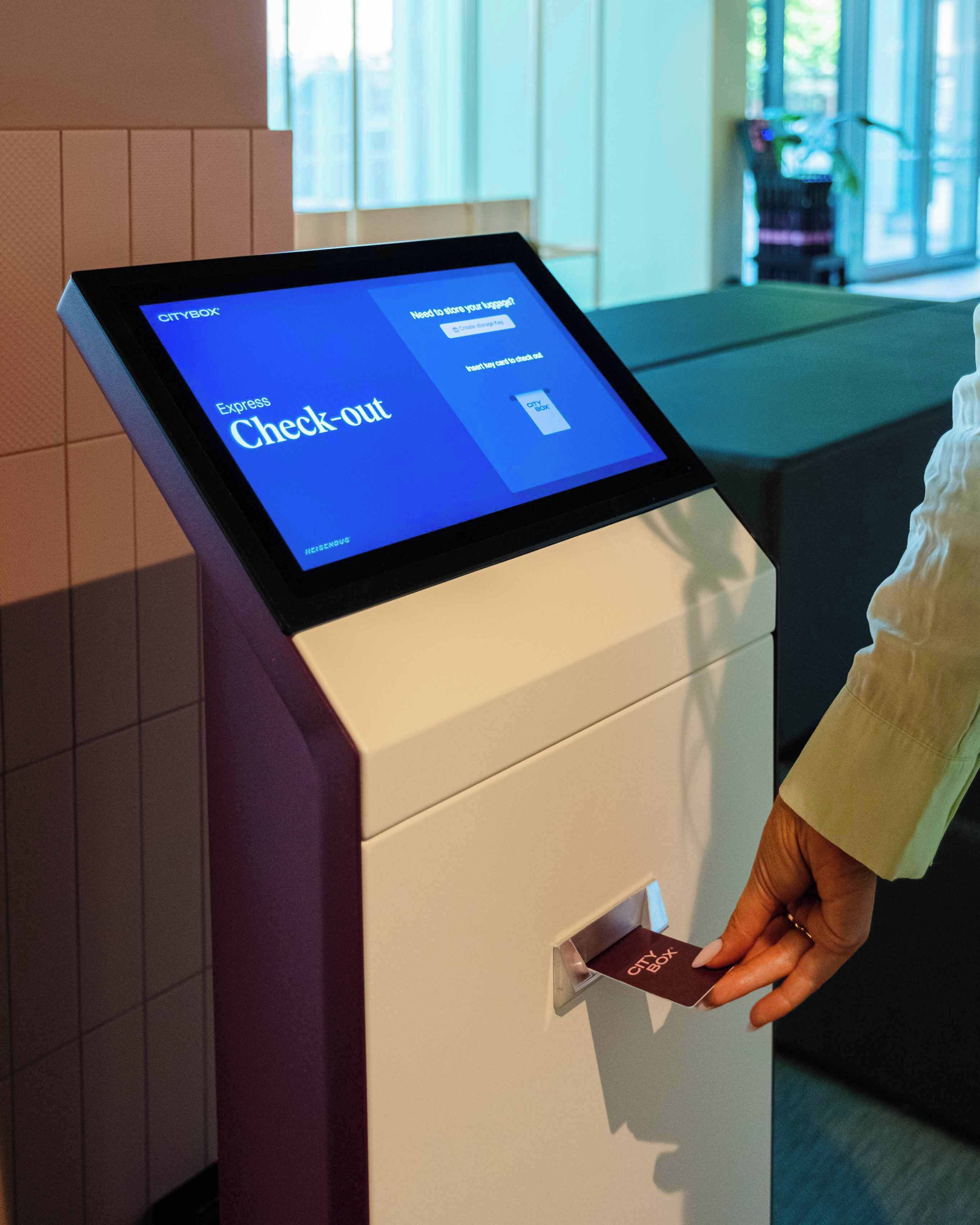 Un kiosque de paiement numérique doté d’un écran affichant la mention « Départ rapide » et d’une main tenant une carte.