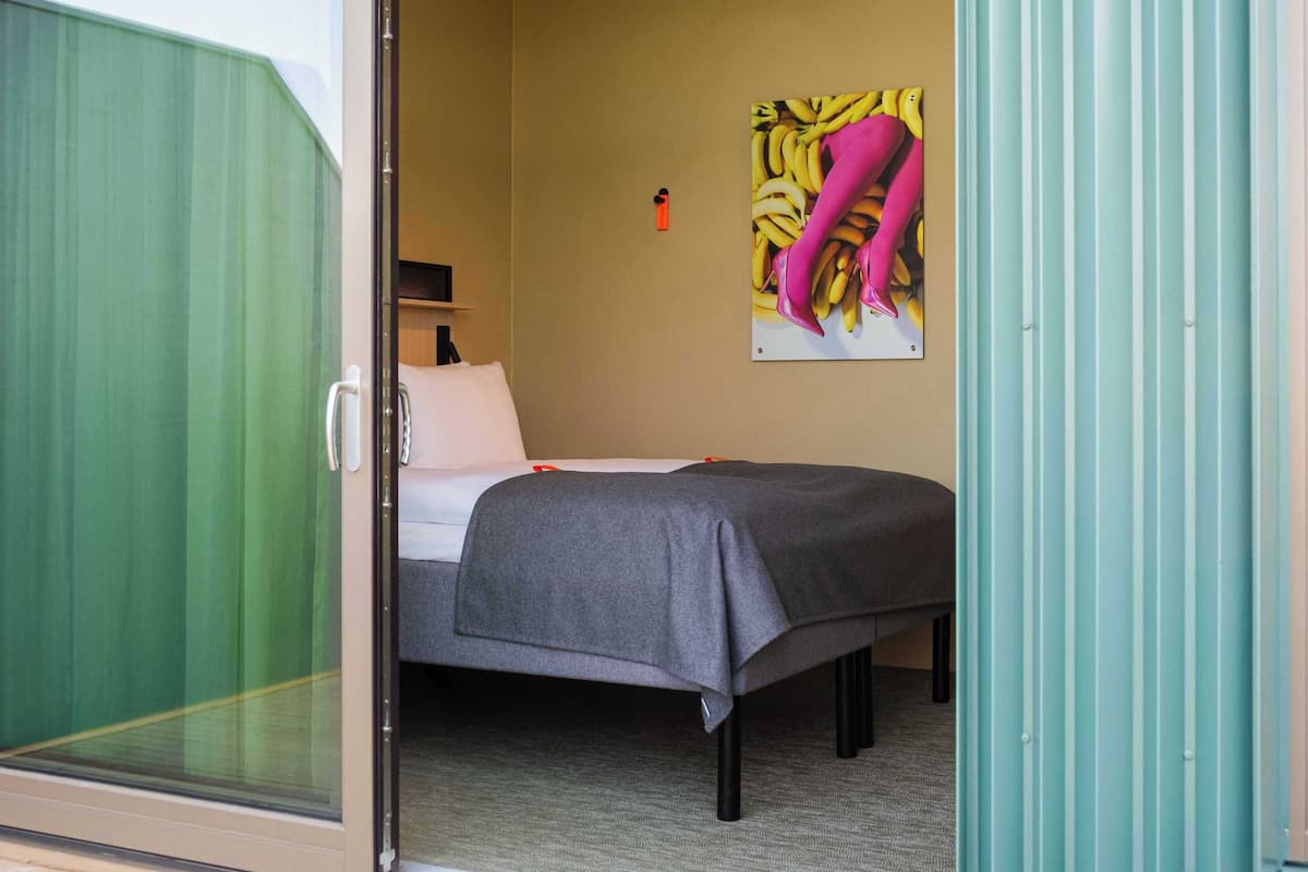 A bedroom with a bed, a pillow, a wall-mounted picture, and a door.