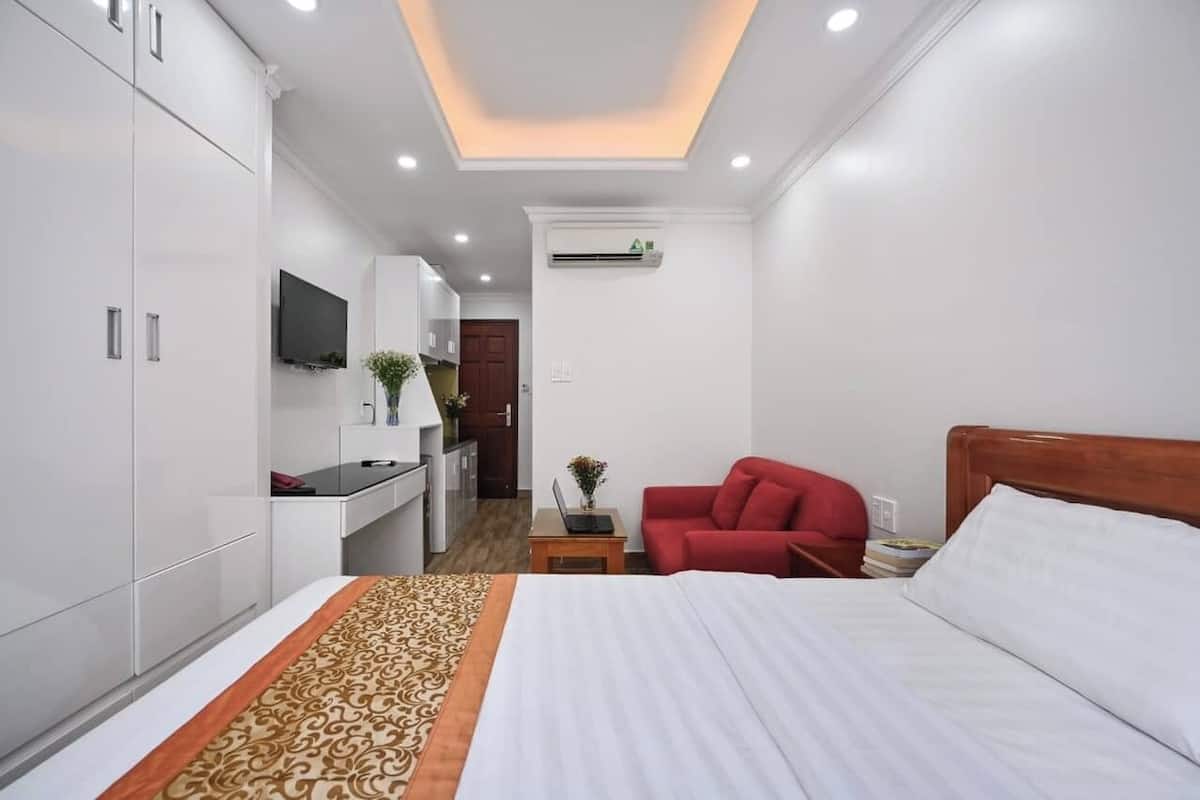 Une chambre d’hôtel avec un lit, un canapé rouge, une télévision et un bureau avec un ordinateur portable.