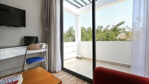 A room with a desk, chair, and a TV mounted on the wall.