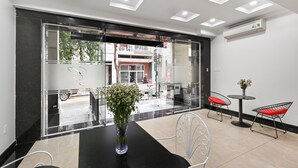 A modern reception area with a glass partition, a black reception desk, and two metal chairs with red cushions.