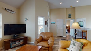 A living room with a flat-screen TV, leather sofas, a coffee table, and a bookshelf. - FH4, Near Beach, Shared Pool, Golf Cart Access (Port Aransas)