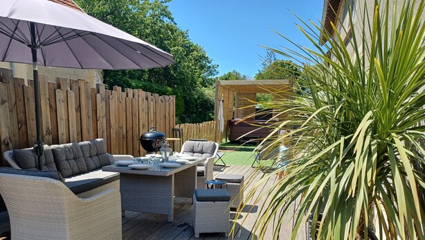 An outdoor patio with wicker furniture, a grill, and a wooden deck.
