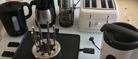 Une cuisine équipée d’une machine à café, d’un grille-pain et d’une bouilloire, le tout posé sur le plan de travail.