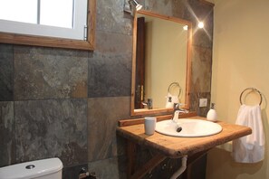 A bathroom with a wooden vanity, a white sink, a large mirror, and a towel ring.