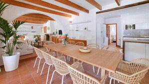 A spacious dining area with a long wooden table, wicker chairs, and a potted plant. - Dream finca: XXL pool, table tennis, BBQ house, volleyball, air-condition (Port de Pollença)