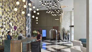 A hotel reception area with a geometric patterned wall, a reception desk, and a check-in counter.